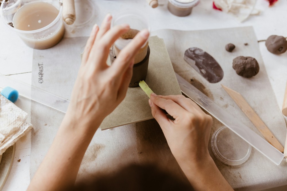 Mains d'une céramiste façonnant une pièce en argile locale récoltée à la main, Atelier Élémen'terre